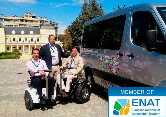 Accessible Madrid team posing in an open space. One is standing and two are sitting on two electric mobility scooters. Next door is an adapted van for accessible travel